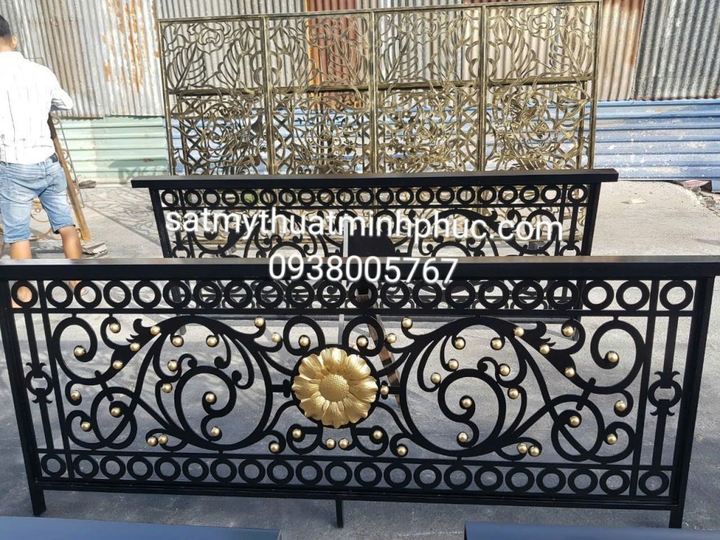 Lan can sắt mỹ thuật màu đen với hoa hướng dương mạ vàng, hoa văn uốn cong mềm mại, đặt trên nền xưởng tôn cấp.