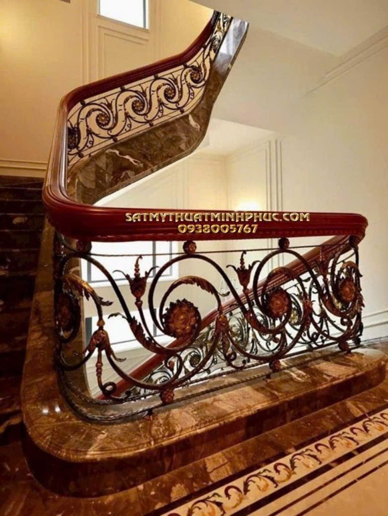 Lan can cầu thang sắt mỹ thuật Minh Phúc họa tiết hoa vàng nổi bật, khung sắt đen, tay vịn gỗ cong mềm mại, nền đá cẩm thạch trắng.