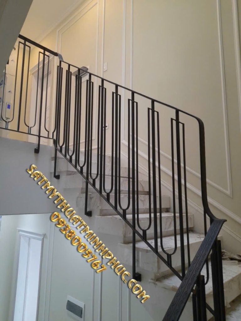 Lan can cầu thang sắt mỹ thuật Minh Phúc khung sắt đen điểm chi tiết mạ vàng, tay vịn gỗ sáng bóng, lắp ở bậc tam cấp lát đá hoa cương.